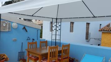 Un patio con una mesa y sillas, una tumbona y vistas a un castillo.