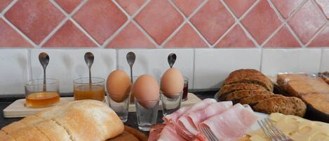 A breakfast spread with bread, eggs, ham, cheese, and a loaf of bread on a wooden board.