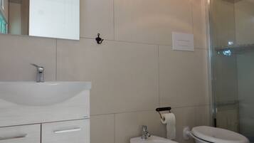Une salle de bain équipée d’un lavabo, d’un bidet et de toilettes.