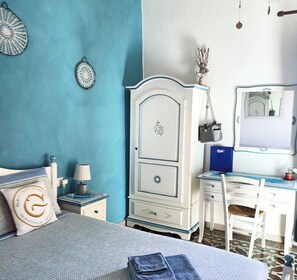 Un dormitorio con una cama, un escritorio y una silla. Hay un aparador con cajones y un espejo.