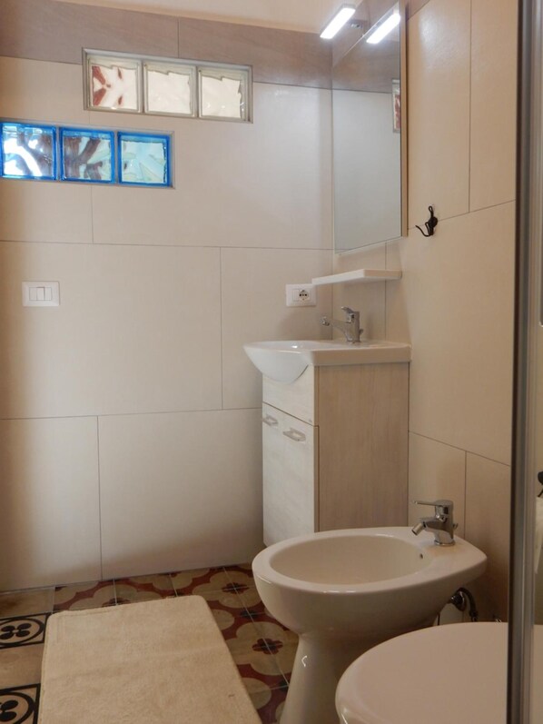 Un baño con inodoro, dos lavamanos, un espejo y un perchero para toallas.
