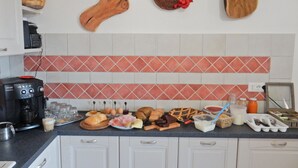 A kitchen with white cabinets, a coffee machine, and various food items on the counter. - B&B Eleonora D'Arborea (Posada)