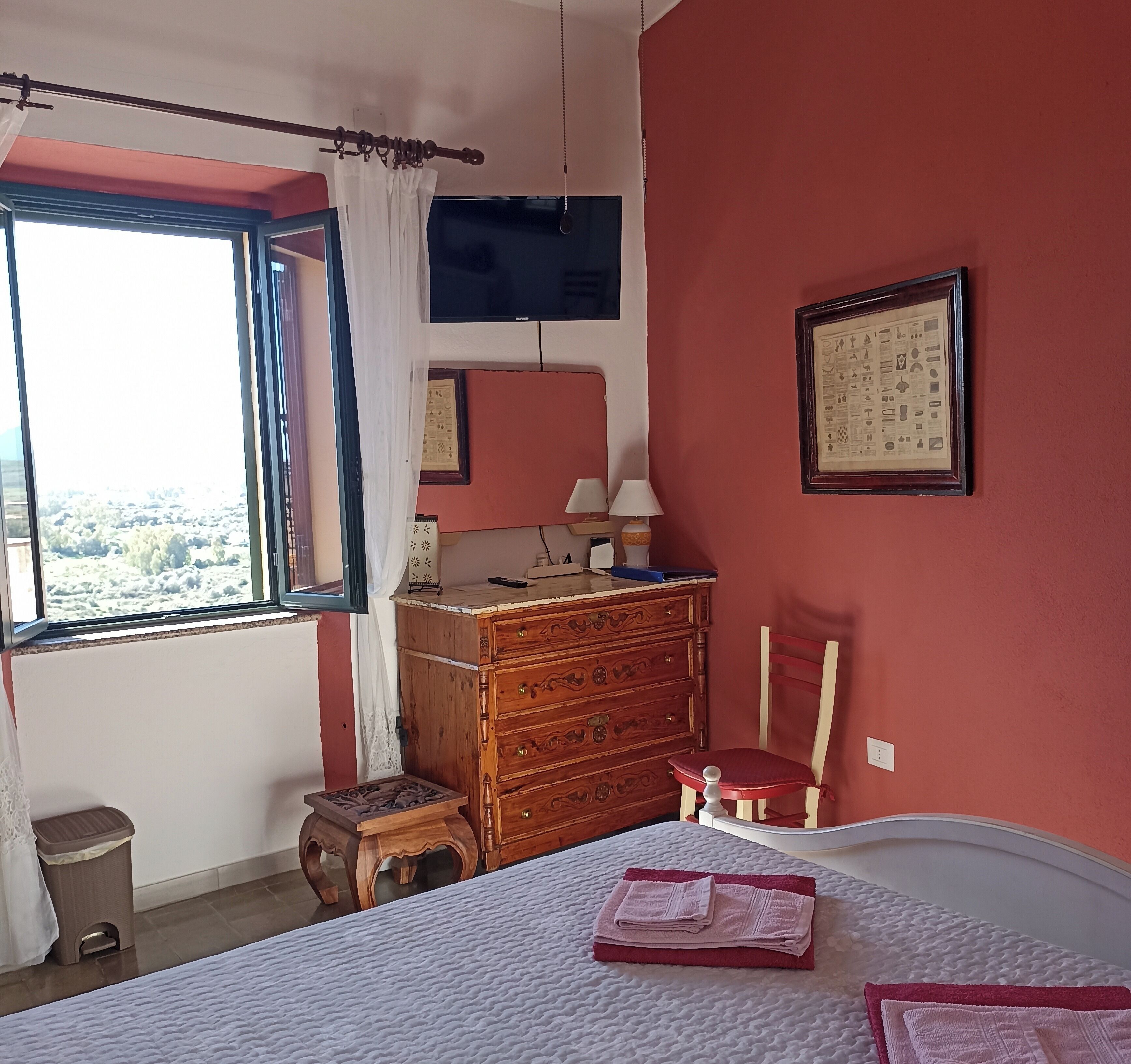 A bedroom with a bed, dresser, chair, and window.
