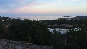 A coastal landscape with a view of the sea, surrounded by dense forest and rocky terrain. - Solferie Holiday Cottage Langenes (Kristiansand)