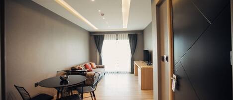A modern living room with a dining area, a sofa, and a TV.
