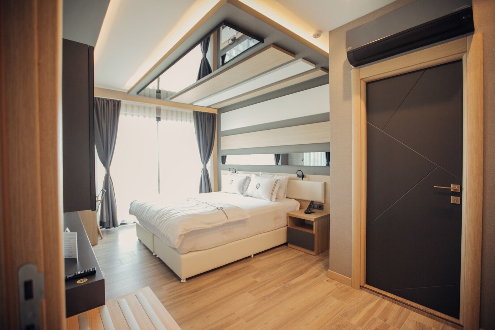 A modern bedroom with a large bed, bedside tables, a wardrobe, and a skylight.