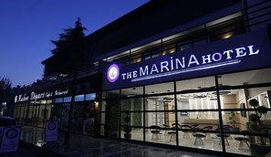 Hotel Marina met een moderne gevel, grote ramen en een zichtbaar restaurant genaamd Kahve Diyari Cafe & Restaurant.