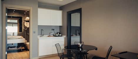 A compact living space with a kitchenette, a dining area with a round table and chairs, and a small sofa.