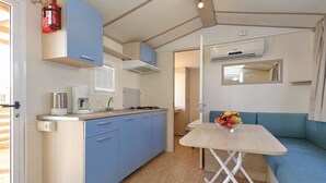 Een kleine keuken met een koffiezetapparaat, fornuis en blauwe kastjes.