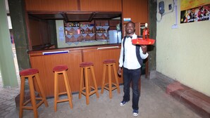 Un espace bar avec des tabourets en bois, un comptoir et des étagères remplies de bouteilles.