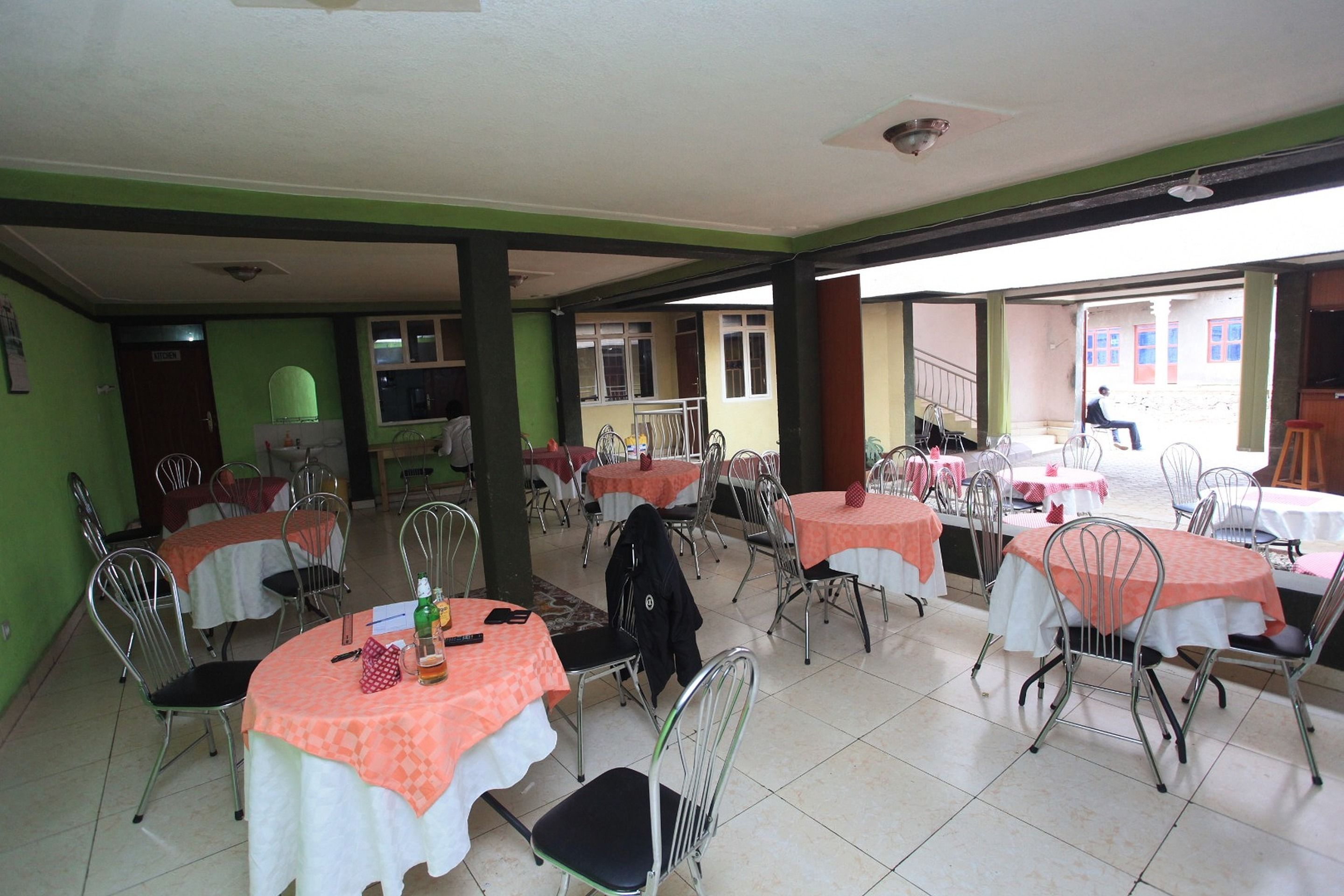 A dining area with multiple tables and chairs, a staircase, and a view of a building outside.