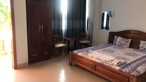 A bedroom with a wooden bed, a wardrobe, a desk, and chairs. - Thanh Trinh Guest House (Binh Kien)