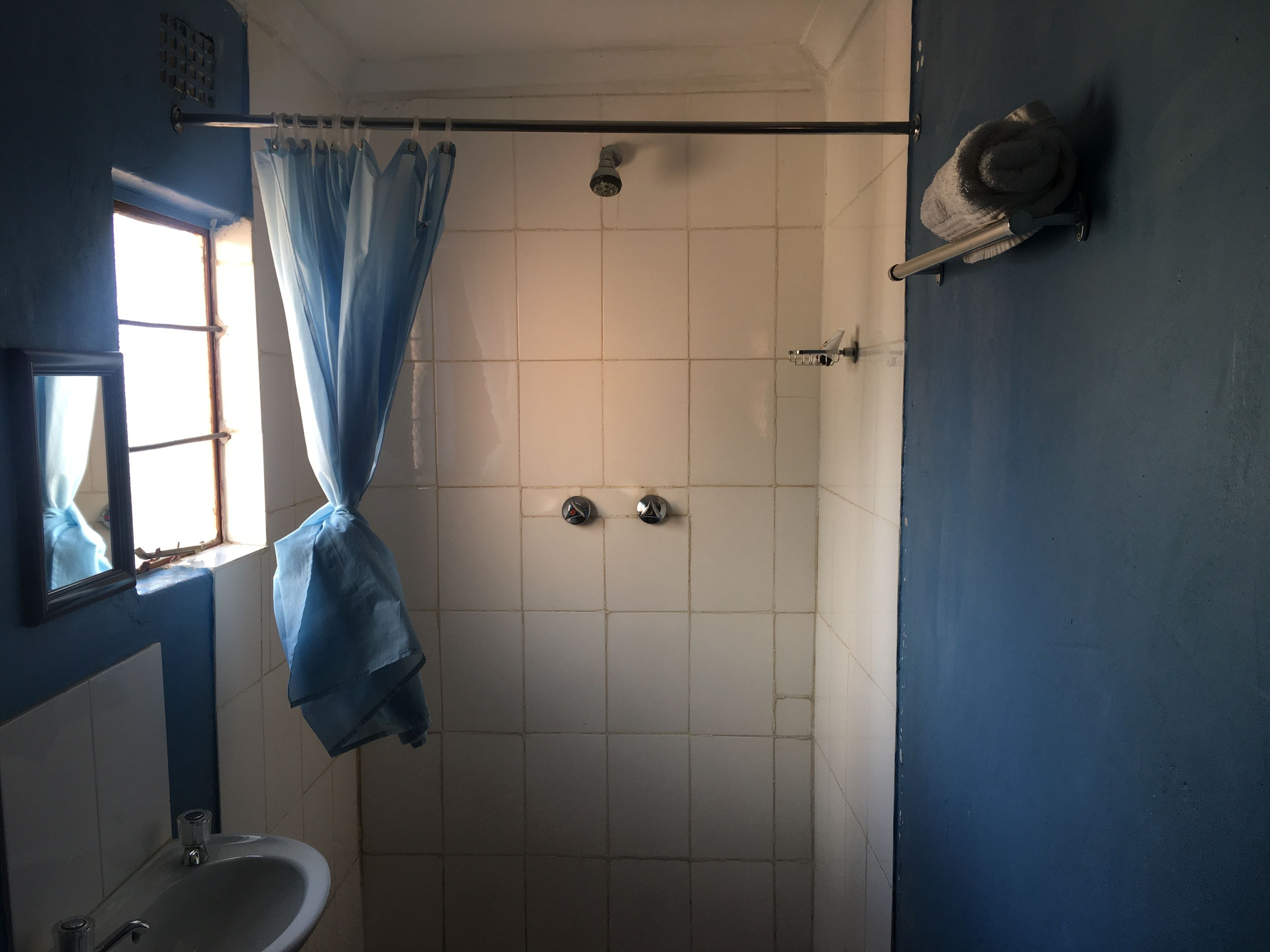 A small, enclosed shower area with a curtain, a sink, and a mirror.