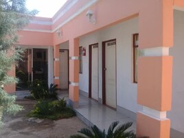 Un edificio con fachada rosa, varias puertas y un pequeño jardín con plantas.