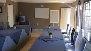 A conference room with a long table, chairs, a whiteboard, and a television. - Kutse Guesthouse (Letlhakeng)