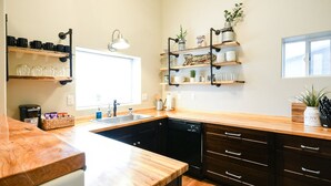 A kitchen with wooden countertops, a dishwasher, and shelves with kitchenware.