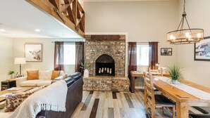 A living room with a stone fireplace, wooden dining table, and a sofa.