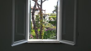 A window with a view of a garden and buildings. - Casa Malò (Ischia)