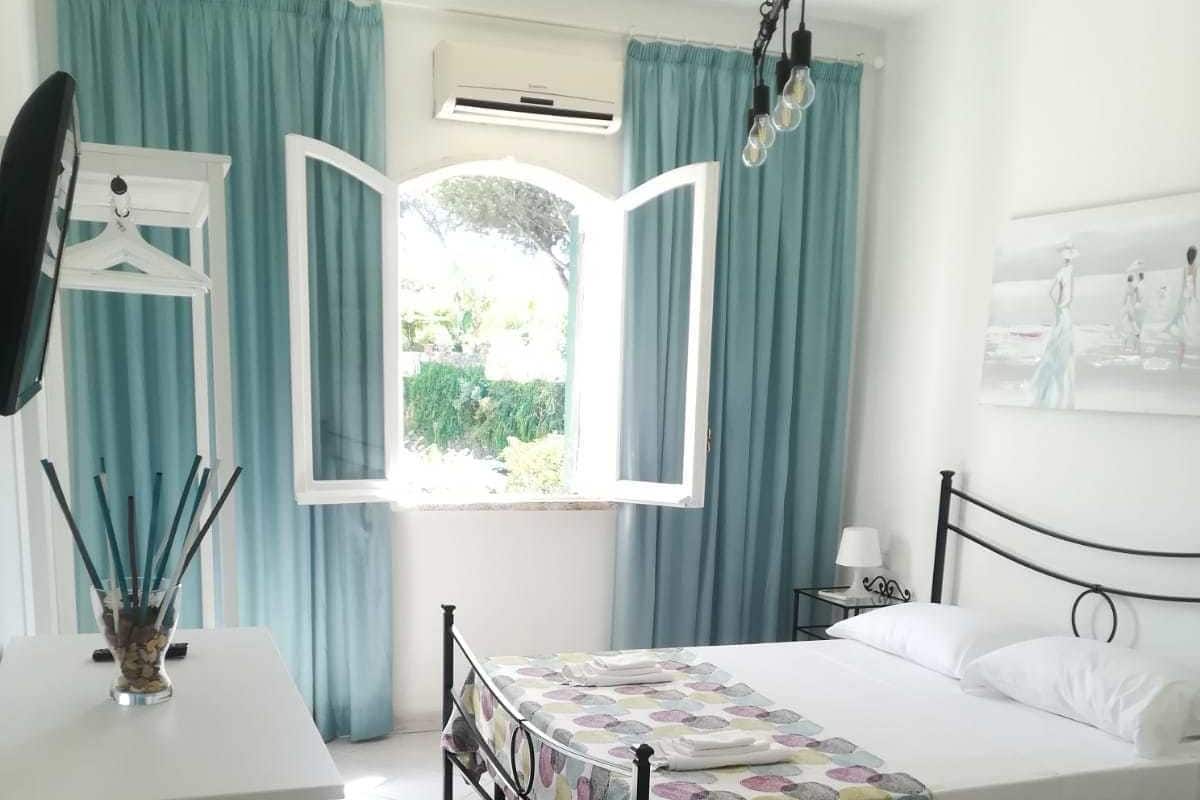 A bedroom with a bed, a desk, and a window with curtains.