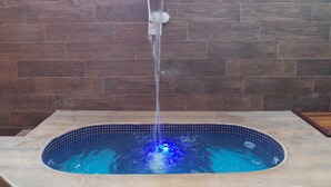 A hot tub with a waterfall feature against a tiled wall. - Cozy chalet in Brotas, SP - Rustic area + Air conditioning (Santa Cecilia II)