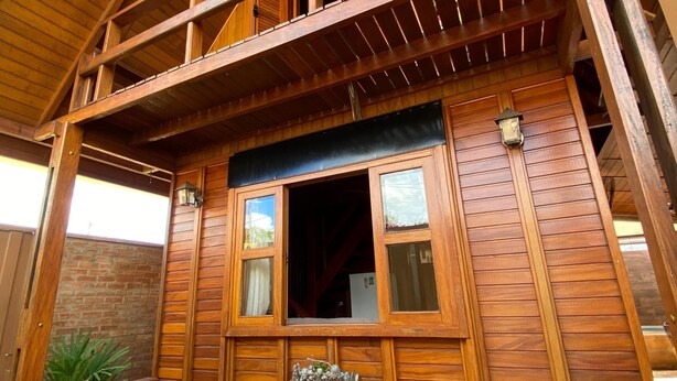 A wooden cabin with a balcony, a front door, and a window. - Cozy chalet in Brotas, SP - Rustic area + Air conditioning (Santa Cecilia II)