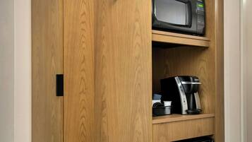 A wooden cabinet with a microwave, coffee maker, and a small refrigerator.