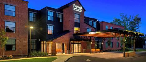 Un hotel Fairfield Inn & Suites by Marriott con fachada de ladrillo, ventanas grandes y un área de estar al aire libre cubierta.