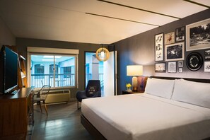 A hotel room with a bed, a desk with a TV, a chair, a balcony view, and artwork on the walls. - Renaissance Minneapolis Bloomington Hotel (Bloomington)