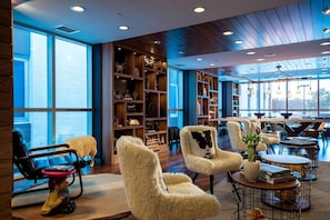 A modern interior with plush chairs, a bookshelf, and a dining area. - Renaissance Minneapolis Bloomington Hotel (Bloomington)