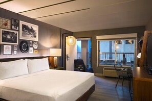 A hotel room with a large bed, a desk with a chair, a desk lamp, a wall-mounted TV, and a large window with a view. - Renaissance Minneapolis Bloomington Hotel (Bloomington)
