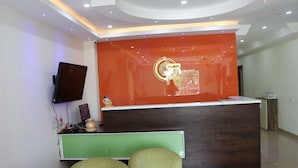 A reception area with a modern design, featuring a reception desk, a flat-screen TV, and a green seating area. - S.R Residency (Dera Bassi)