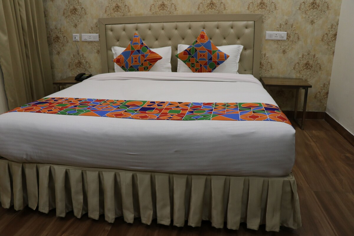 A bed with a white duvet, a colorful geometric-patterned throw, and a decorative headboard.