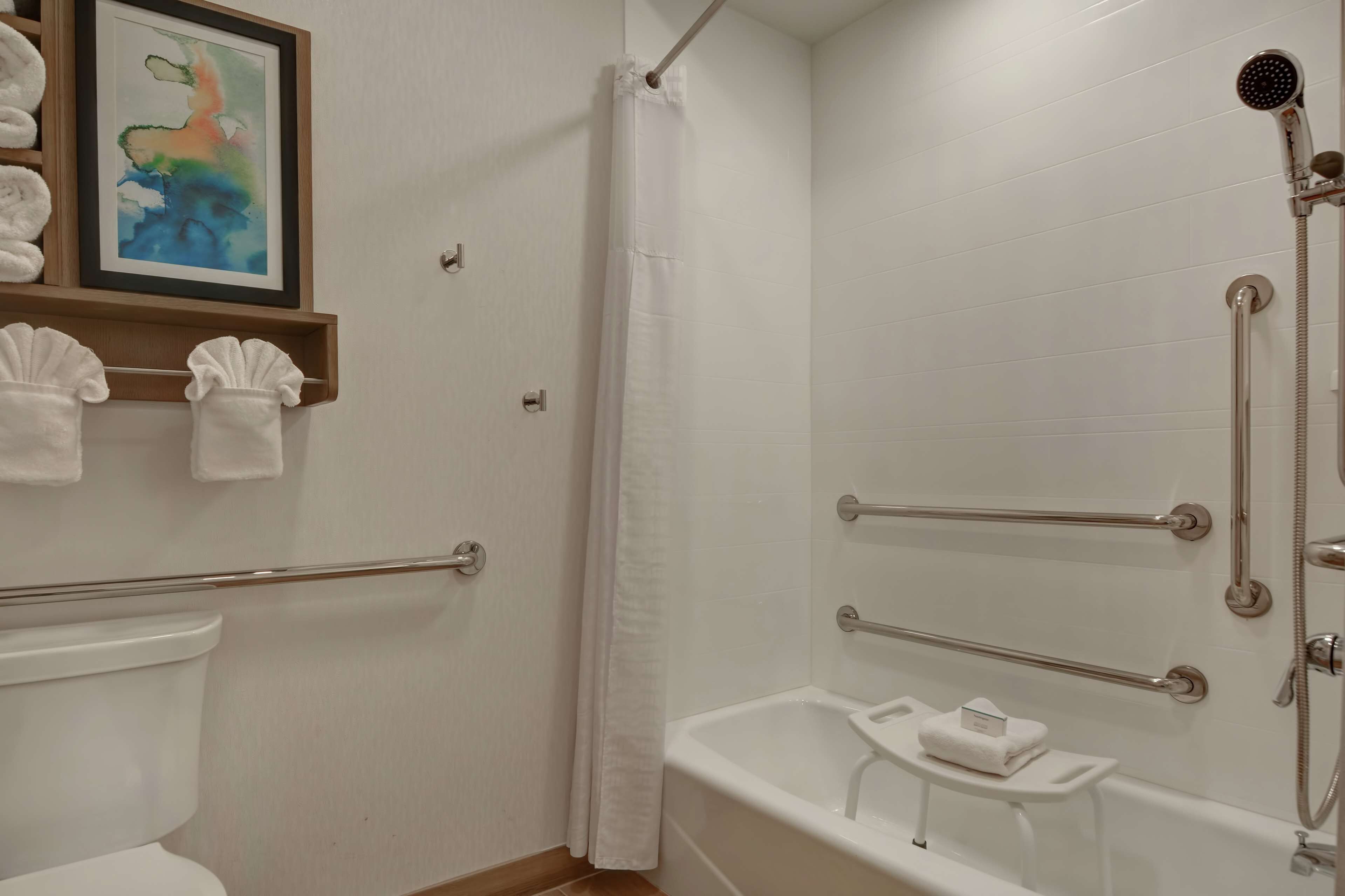 Een badkamer met douche, toilet en een klein wastafeltje met een handdoek.