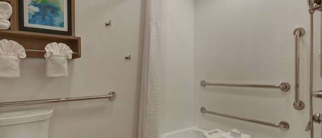 Een badkamer met douche, toilet en een klein wastafeltje met een handdoek.