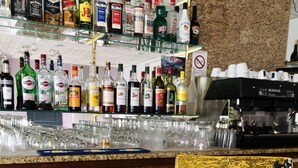 A bar area with a variety of liquor bottles and glasses on shelves. - Hôtel Restaurant La Diligence (Le Brignon)