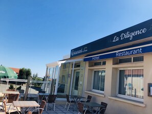 Een restaurant genaamd 'La Diligence' met terras en een bord dat het ook als hotel fungeert.