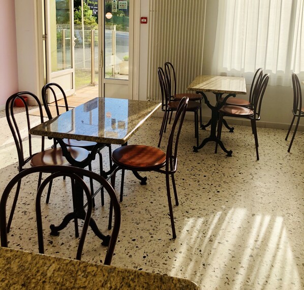 A dining area with a glass-top table and metal chairs. - Hôtel Restaurant La Diligence (Le Brignon)