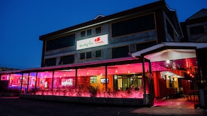 A building with a sign reading "Maple Inn" and a covered outdoor area with seating. - Maple Inn Hotel (Ruiru)