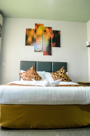 A neatly made bed with a green headboard, white bedding, and patterned pillows.