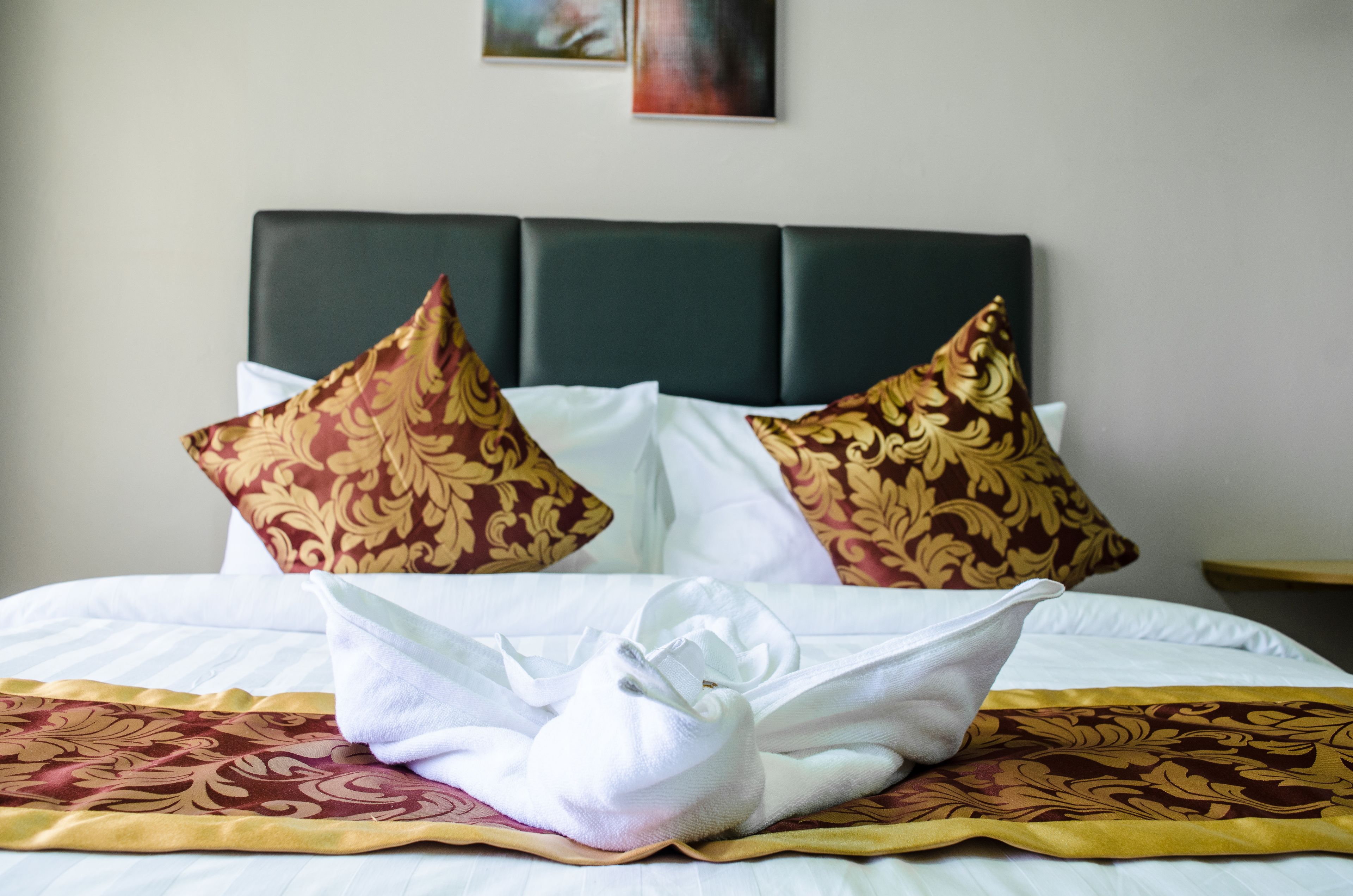 A neatly made bed with patterned pillows and a white towel.