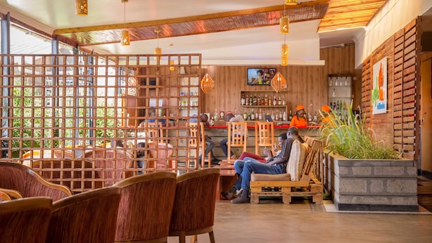 A cozy bar area with wooden furniture, a bar counter, and a seating area with chairs. - Maple Inn Hotel (Ruiru)