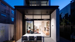 Ein modernes Haus mit einer großen Glasdoor, die in einen Essbereich und eine Küche führt.