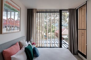 Ein Hotelzimmer mit einem Bett, Kissen, einem Gemälde und Blick durch ein großes Fenster.
