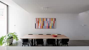 A modern dining area with a wooden table, black chairs, and a colorful abstract painting on the wall.