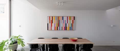Ein zeitgemäßer Essbereich mit einem Holztisch, schwarzen Stühlen und einem farbenfrohen, abstrakten Gemälde an der Wand.