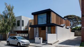 A modern two-story house with a car parked in the driveway.
