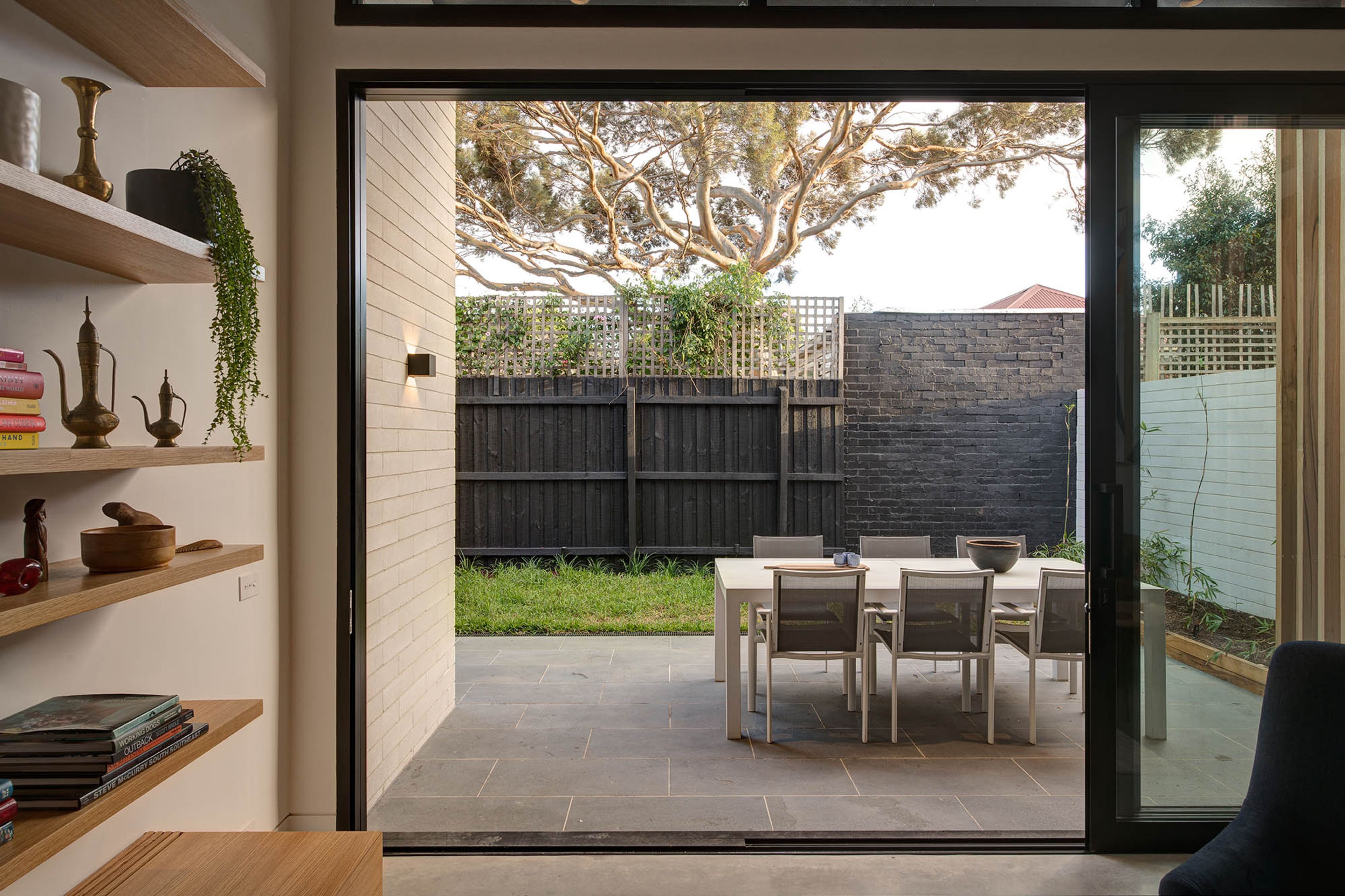 A modern interior with a sliding glass door leading to an outdoor patio with a table and chairs.