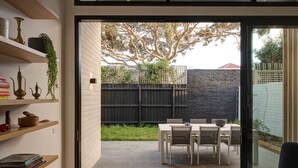 A modern interior with a sliding glass door leading to an outdoor patio with a table and chairs. - Woodfin House Pet Friendly Home in Abbotsford (Abbotsford)