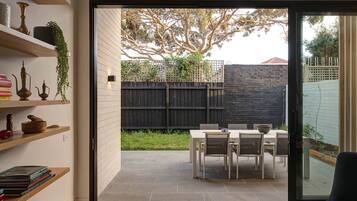 A modern interior with a sliding glass door leading to an outdoor patio with a table and chairs.