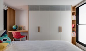 A bedroom with a bed, a desk with a globe and an abacus, a red chair, and a bookshelf.